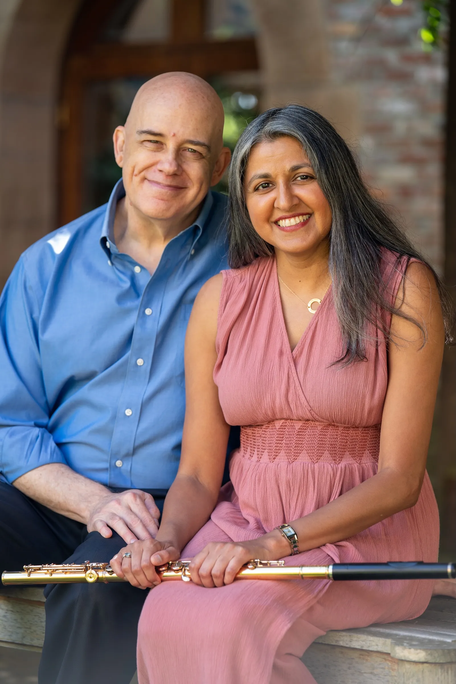 Brian Shaw and Sujatha Maheshwari seated outdoors, flutes resting across their laps.