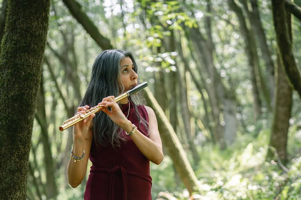 Sujatha Maheshwari playing flute among trees.